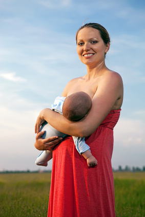 Young woman breastfeeding her baby outdoors